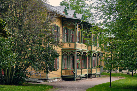 Ronneby Blekinge County Sweden 11 September 2025 View of a historic yellow wooden villa with green trim and balconies in the lush Brunssparken park. Ronneby Blekinge County Sweden 11 September 2025 View of a historic yellow wooden villa with green trim and balconies in the lush Brunssparken park.