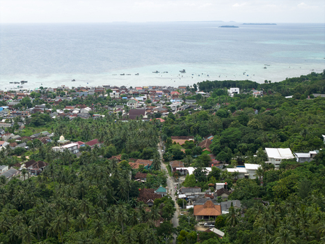 Aerial view of a lush landscape meeting the turquoise sea dotted with buildings and trees Karimunjawa Central Java Indonesia. Aerial view of a lush landscape meeting the turquoise sea dotted with buildings and trees Karimunjawa Central Java Indonesia.
