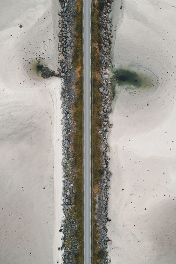 Aerial view of Midnattsolveien road cutting through a sandy landscape with rocky embankments in Laukvik Nordland Norway. Aerial view of Midnattsolveien road cutting through a sandy landscape with rocky embankments in Laukvik Nordland Norway.