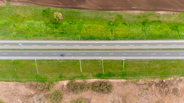 Aerial view of vehicles traversing a multi lane highway framed by vibrant green fields against contrasting brown earth Sremska Mitrovica Vojvodina Serbia. Aerial view of vehicles traversing a multi lane highway framed by vibrant green fields against contrasting brown earth Sremska Mitrovica Vojvodina Serbia.