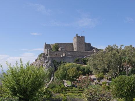 View of the historic stone walls and towers of Marvao Castle perched on a rocky hilltop surrounded by lush greenery under a clear blue sky in Marvao Portalegre District Portugal. View of the historic stone walls and towers of Marvao Castle perched on a rocky hilltop surrounded by lush greenery under a clear blue sky in Marvao Portalegre District Portugal.