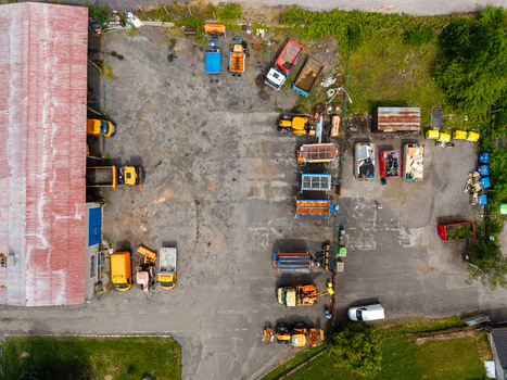 Aerial view of a construction equipment yard with trucks trailers and heavy machinery parked on a paved lot next to a warehouse building in Zebrak Central Bohemian Region Czechia. Aerial view of a construction equipment yard with trucks trailers and heavy machinery parked on a paved lot next to a warehouse building in Zebrak Central Bohemian Region Czechia.