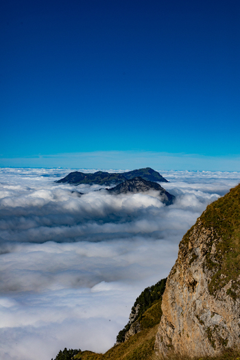 Aerial view of the Swiss Alps with mountain peaks rising above a dense sea of clouds under a clear blue sky in Airolo Ticino Switzerland. Aerial view of the Swiss Alps with mountain peaks rising above a dense sea of clouds under a clear blue sky in Airolo Ticino Switzerland.