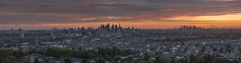 Aerial view of the London skyline at sunset featuring dense urban rooftops and distant skyscrapers under a vibrant orange sky in Wandsworth London United Kingdom.