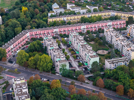 Aerial view of High Deck Siedlung residential complex with colorful pink and green facades surrounded by lush green trees and urban streets in Berlin Berlin Germany. Aerial view of High Deck Siedlung residential complex with colorful pink and green facades surrounded by lush green trees and urban streets in Berlin Berlin Germany.