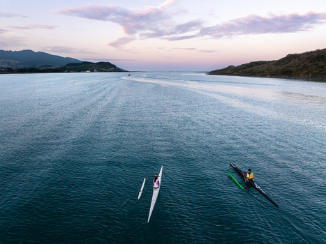 Raglan New Zealand 09 February 2026 Aerial view of people kayaking in the calm waters of the bay at sunset with rolling hills in the background.