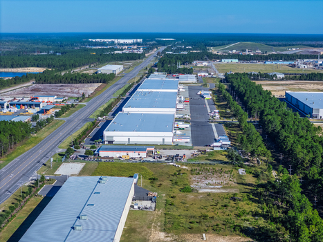 Wilmington North Carolina United States 27 September 2026 Aerial view of industrial warehouse complex with loading docks and trucks parked near a highway and pine forests. Wilmington North Carolina United States 27 September 2026 Aerial view of industrial warehouse complex with loading docks and trucks parked near a highway and pine forests.