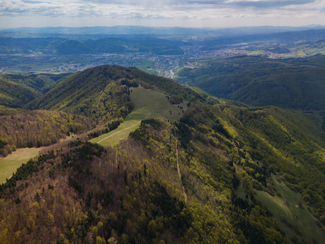 Aerial view of Predny Diel ridge featuring green meadows and dense forests under a cloudy sky in Spania Dolina Banskobystricky kraj Slovakia.