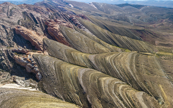 Aerial view of the Gigantes Dormidos geological formation featuring dramatic folded rock strata rugged mountain ridges and arid desert terrain in Tres Cruces Jujuy Province Argentina. Aerial view of the Gigantes Dormidos geological formation featuring dramatic folded rock strata rugged mountain ridges and arid desert terrain in Tres Cruces Jujuy Province Argentina.