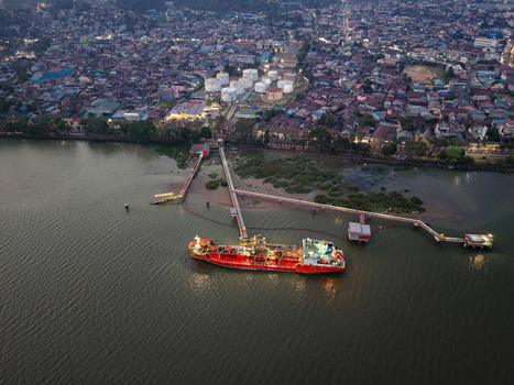 Aerial view of PT. Pertamina TBBM Samarinda fuel storage facility with a red tanker ship docked at the pier on the Mahakam River in Samarinda Kalimantan Timur Indonesia.