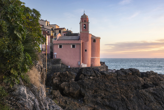 View of the pink church of San Giorgio perched on the rocky cliffs by the sea during sunset in Tellaro Liguria Italy. View of the pink church of San Giorgio perched on the rocky cliffs by the sea during sunset in Tellaro Liguria Italy.