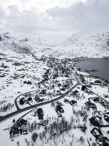 Aerial view of the snow covered village nestled between steep mountains and the calm waters of the fjord in Ersfjord Troms Norway. Aerial view of the snow covered village nestled between steep mountains and the calm waters of the fjord in Ersfjord Troms Norway.