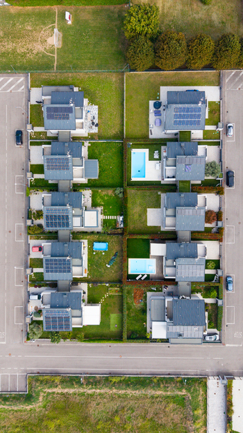 Aerial view of modern residential houses featuring solar panels on rooftops private swimming pools and green lawns in a suburban neighborhood in Milan Lombardy Italy. Aerial view of modern residential houses featuring solar panels on rooftops private swimming pools and green lawns in a suburban neighborhood in Milan Lombardy Italy.