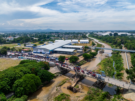 Aerial view of Ouanaminthe Market with busy crowds vehicles crossing the bridge over the river and surrounding urban landscape Ouanaminthe Arrondissement Nord Est Department Haiti.