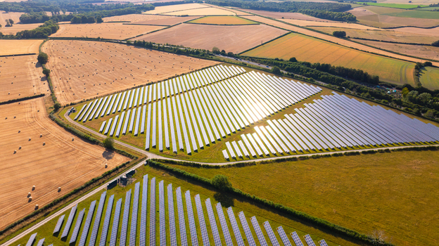 Aerial view of a solar farm with rows of photovoltaic panels situated in agricultural fields with hay bales and green pastures in the countryside in Dorset England United Kingdom. Aerial view of a solar farm with rows of photovoltaic panels situated in agricultural fields with hay bales and green pastures in the countryside in Dorset England United Kingdom.