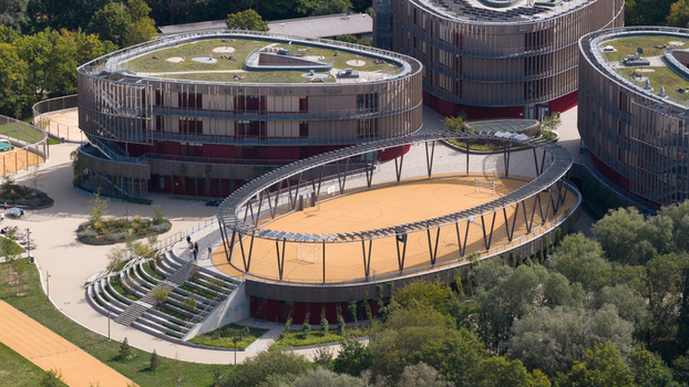 Durmersheim Germany 12 September 2026 Aerial view of Wilhelm Hausenstein Gymnasium with modern oval buildings green roofs and a central sports field under a pergola structure.