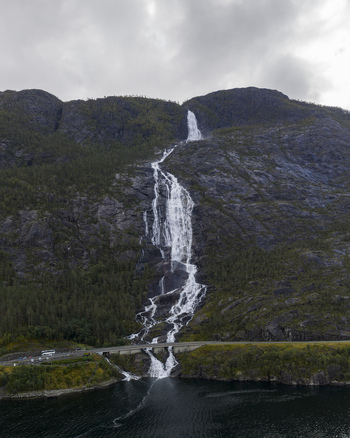 Aerial view of Langfossen waterfall cascading down steep rocky cliffs into the Akrafjorden under an overcast sky Fjaera Vestland Norway. Aerial view of Langfossen waterfall cascading down steep rocky cliffs into the Akrafjorden under an overcast sky Fjaera Vestland Norway.