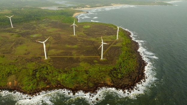 Aerial view of Devgad Windmills situated on a coastal cliff with green landscape rocky shoreline and waves crashing against the rocks in Devgad Maharashtra India. Aerial view of Devgad Windmills situated on a coastal cliff with green landscape rocky shoreline and waves crashing against the rocks in Devgad Maharashtra India.