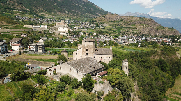 Aerial view of the historic stone castle of Sarriod de la Tour surrounded by lush green trees and vineyards in a mountain valley Aosta Valley Aosta Valley Italy. Aerial view of the historic stone castle of Sarriod de la Tour surrounded by lush green trees and vineyards in a mountain valley Aosta Valley Aosta Valley Italy.