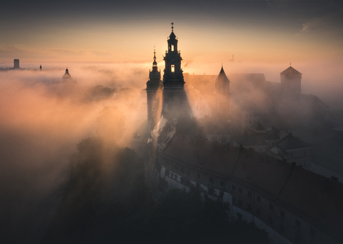 Aerial view of Wawel Royal Castle and Cathedral shrouded in thick morning fog during a golden sunrise in Krakow Lesser Poland Voivodeship Poland.
