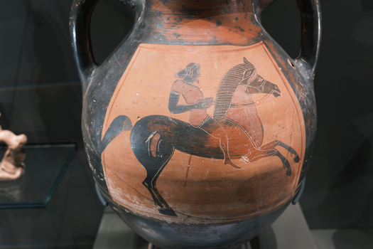Giza Egypt 16 May 2026 View of an ancient Greek amphora featuring a detailed black figure illustration of a man riding a horse on display at the Grand Egyptian Museum.