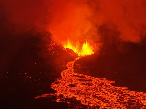 Aerial view of a volcanic eruption with glowing lava flowing down the dark terrain in Reykjavik Reykjavikurborg Iceland.