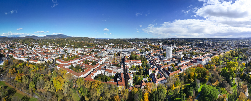 Aerial view of autumn foliage surrounding the urban sprawl of Geidorf and the university district with red rooftops and a distant mountainous skyline Graz Styria Austria.