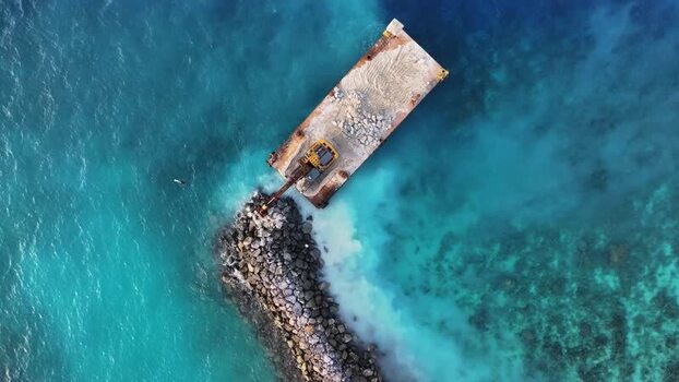 Aerial view of an excavator on a barge building a breakwater Maldives. Aerial view of an excavator on a barge building a breakwater Maldives.