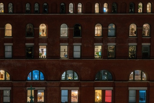 Aerial view of the illuminated facade of a brick office building at night featuring rows of arched windows with warm and cool interior lighting New York New York United States. Aerial view of the illuminated facade of a brick office building at night featuring rows of arched windows with warm and cool interior lighting New York New York United States.