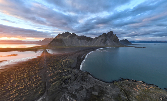 Aerial view of dramatic Vestrahorn mountain rising from black sand beach the sun casting a golden glow on the landscape Höfn Iceland. Aerial view of dramatic Vestrahorn mountain rising from black sand beach the sun casting a golden glow on the landscape Höfn Iceland.