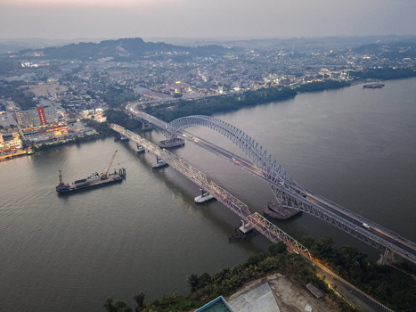 Aerial view of Jembatan Mahakam I spanning the Mahakam River with urban development and a barge in the water in Kecamatan Samarinda Seberang Kalimantan Timur Indonesia. Aerial view of Jembatan Mahakam I spanning the Mahakam River with urban development and a barge in the water in Kecamatan Samarinda Seberang Kalimantan Timur Indonesia.