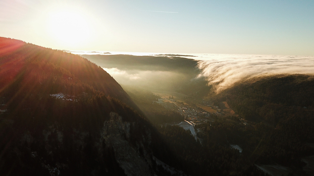Aerial view of flowing fog and sunrise over the valley in Mijoux Auvergne Rhone Alpes France.