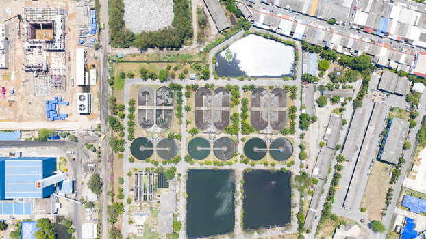 Aerial view of a wastewater treatment plant with circular sedimentation tanks and rectangular aeration basins surrounded by industrial buildings and greenery in Phuket Phuket Thailand. Aerial view of a wastewater treatment plant with circular sedimentation tanks and rectangular aeration basins surrounded by industrial buildings and greenery in Phuket Phuket Thailand.