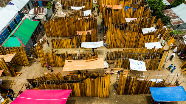 Aerial view of Baish Mowza Sarak Bazar with stacks of wooden planks and timber arranged in rows with people walking through the market area in Nabinagar Chittagong Division Bangladesh. Aerial view of Baish Mowza Sarak Bazar with stacks of wooden planks and timber arranged in rows with people walking through the market area in Nabinagar Chittagong Division Bangladesh.