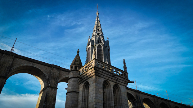 Aerial view of the Gothic spire of Eglise Saint Melaine de Morlaix and the historic stone viaduct under a deep blue sky Morlaix Bretagne France. Aerial view of the Gothic spire of Eglise Saint Melaine de Morlaix and the historic stone viaduct under a deep blue sky Morlaix Bretagne France.