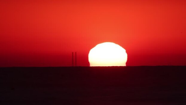 View of red sunset over ocean with distant silhouettes France.