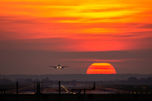 View of an airplane approaching the runway at Bucharest Henri Coanda International Airport during a vibrant sunset with glowing orange sky in Otopeni Judetul Ilfov Romania. View of an airplane approaching the runway at Bucharest Henri Coanda International Airport during a vibrant sunset with glowing orange sky in Otopeni Judetul Ilfov Romania.