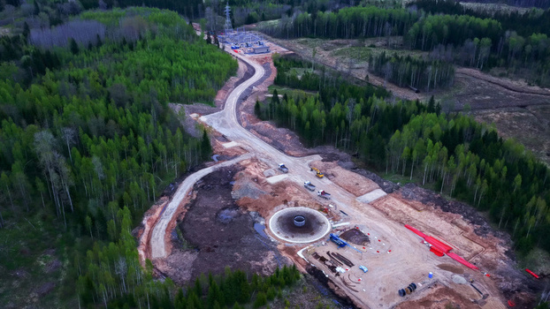 Aerial view of a wind turbine foundation under construction with heavy machinery and dirt roads surrounded by a dense forest in Latvija. Aerial view of a wind turbine foundation under construction with heavy machinery and dirt roads surrounded by a dense forest in Latvija.