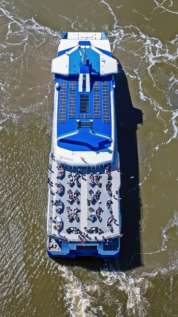 Aerial view of a ferry boat with passengers on the deck and solar panels on the roof sailing through the water in Harlingen Friesland Netherlands.