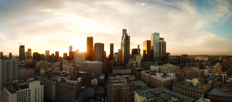 Aerial view of the Los Angeles skyline at sunset with golden light reflecting off glass skyscrapers and urban buildings in Los Angeles California United States.