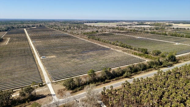 Aerial view of rows of solar panels stretch across the landscape contrasting with the blue sky and green tree line Elkton Florida United States. Aerial view of rows of solar panels stretch across the landscape contrasting with the blue sky and green tree line Elkton Florida United States.