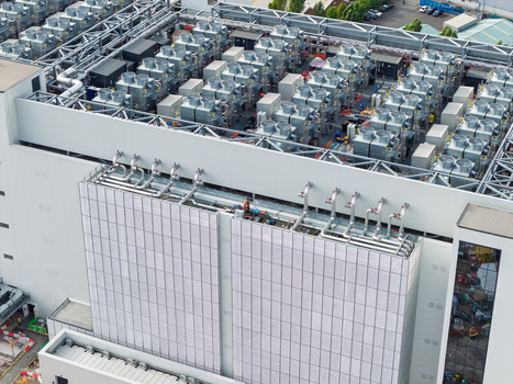 Aerial view of a modern data center featuring extensive rooftop cooling units industrial HVAC systems and complex piping infrastructure in the United Kingdom. Aerial view of a modern data center featuring extensive rooftop cooling units industrial HVAC systems and complex piping infrastructure in the United Kingdom.