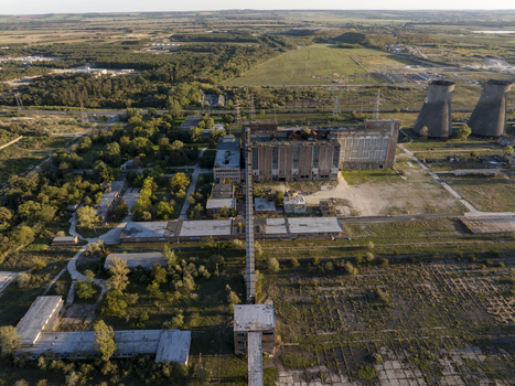 Aerial view of the abandoned Inota Power Plant with its iconic cooling towers and industrial structures set amidst rural fields and trees in Varpalota Hungary. Aerial view of the abandoned Inota Power Plant with its iconic cooling towers and industrial structures set amidst rural fields and trees in Varpalota Hungary.