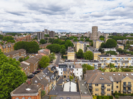 Aerial view of the Shoreditch district featuring dense residential architecture lush green trees and a distant city skyline in London England United Kingdom. Aerial view of the Shoreditch district featuring dense residential architecture lush green trees and a distant city skyline in London England United Kingdom.