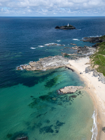 Aerial view of Godrevy Beach featuring turquoise waters rocky outcrops and the Godrevy Lighthouse on an island in the distance Gwithian England United Kingdom. Aerial view of Godrevy Beach featuring turquoise waters rocky outcrops and the Godrevy Lighthouse on an island in the distance Gwithian England United Kingdom.