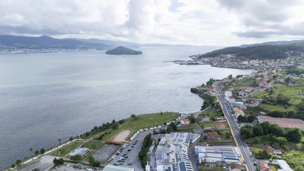 Aerial view of the coastal town of Casalvito featuring the bay with a small island and lush green hills under a cloudy sky in Casalvito Pontevedra Spain. Aerial view of the coastal town of Casalvito featuring the bay with a small island and lush green hills under a cloudy sky in Casalvito Pontevedra Spain.