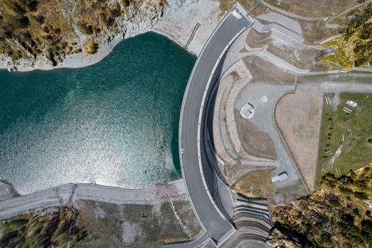 Aerial view of the Beauregard Dam and turquoise reservoir water surrounded by rocky mountain slopes in Valgrisenche Aosta Valley Italy.
