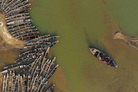Aerial view of Jadukata River with numerous wooden boats moored along the sandy bank and a passenger boat navigating the water in Sunamganj Sylhet Division Bangladesh. Aerial view of Jadukata River with numerous wooden boats moored along the sandy bank and a passenger boat navigating the water in Sunamganj Sylhet Division Bangladesh.
