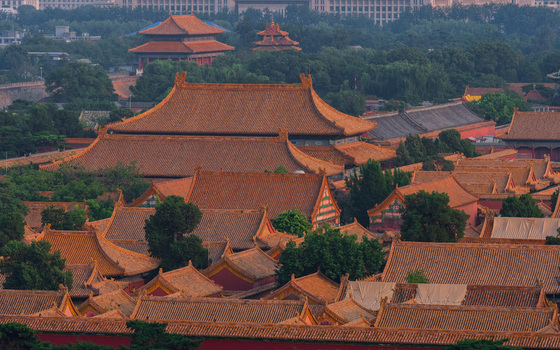 View of the Forbidden City with its iconic golden tiled roofs and traditional Chinese architecture set against lush trees in Beijing Beijing China. View of the Forbidden City with its iconic golden tiled roofs and traditional Chinese architecture set against lush trees in Beijing Beijing China.