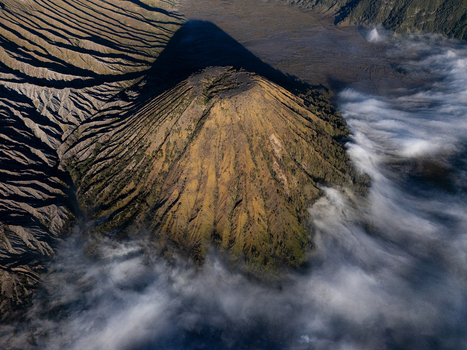 Aerial view of Mount Bromo with its volcanic crater dramatic shadows and surrounding clouds in Kecamatan Sukapura Jawa Timur Indonesia.
